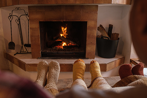 Socked feet of family members in front of fireplace cared for by chimney service in Lacey