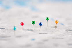 multiple colored pins on a blurry map